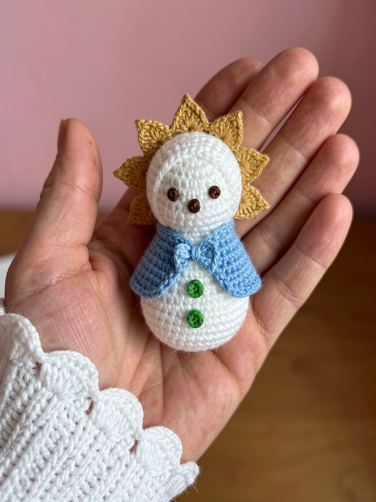 Amigurumi de Nossa Senhora das Graças com manto azul e branco, sobre fundo neutro
