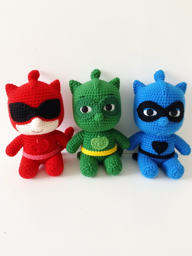 Amigurumi do PJ Masks com orelhas pontudas e capa azul, em crochê, sobre fundo neutro.